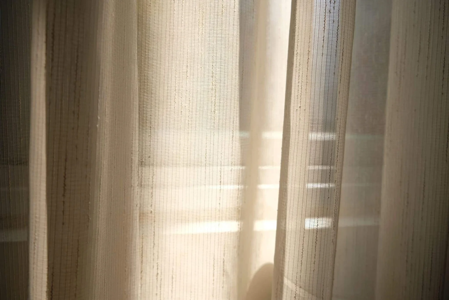 Soft natural light falling across textured curtains at the Haus